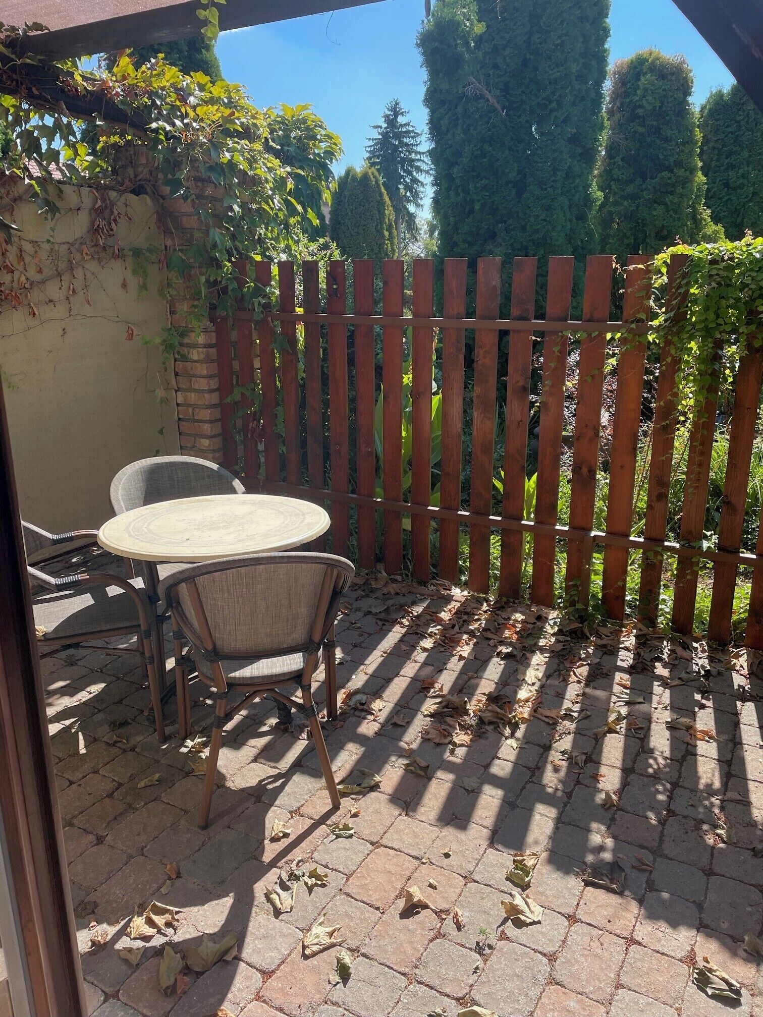 Eine Terrasse im Freien mit Holzlattenzaun, einem Tisch und zwei Stühlen.