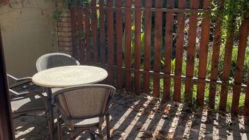 Eine Terrasse im Freien mit Holzlattenzaun, einem Tisch und zwei Stühlen.