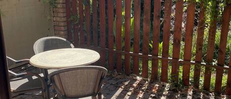 An outdoor patio with a wooden fence, a table, and two chairs.