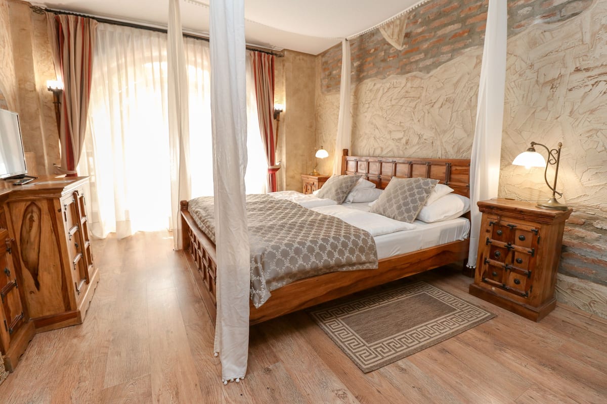 Un dormitorio con cama de madera, mesita de noche, lámpara y una alfombra decorativa.