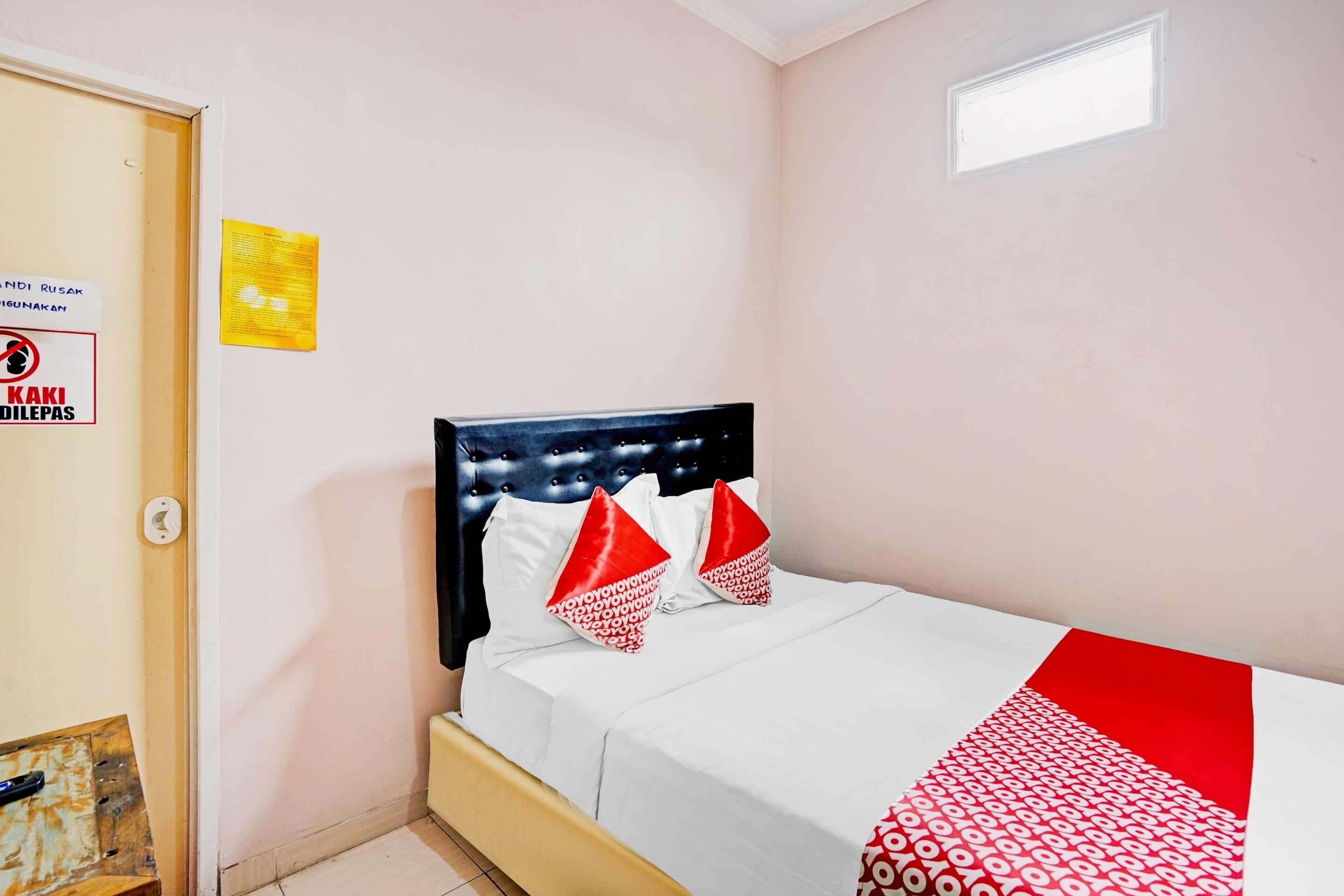 A bedroom with a bed, a headboard, a window, and a door.