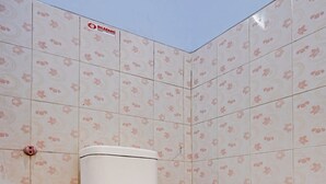 Een badkamer met een toilet, een handdesinfecteerder en een betegelde muur met een bloemenpatroon.
