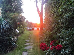 A garden pathway with stepping stones leading to a pool area, surrounded by lush greenery and flowering plants. - Propriété Campagne à 65 kms de Paris. Piscine et Tennis. Période JO Paris 2024 (Mulcent)