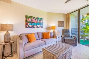 A living room with a sofa, two lamps, a chair, and a painting.