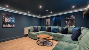Ein modernes Wohnzimmer mit einem grünen Ecksofa, einem Holztisch und gerahmten Kunstwerken an den Wänden.