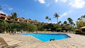 A swimming pool surrounded by palm trees and lounge chairs, with a hotel building in the background. - Kamaole Sands #2-401 Beautifully Renovated Suite, Family Friendly, A/C! (Kihei)