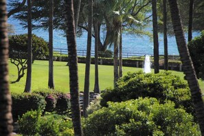 Un jardin bien entretenu, agrémenté d’une fontaine, de palmiers et offrant une vue sur la mer.