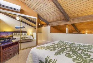 Une chambre dotée d’un grand lit, d’une télévision et d’une porte-fenêtre coulissante donnant sur une salle de bain.