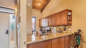 A kitchen with wooden cabinets, a granite countertop, and a stainless steel sink. - Kamaole Sands #2-401 Beautifully Renovated Suite, Family Friendly, A/C! (Kihei)
