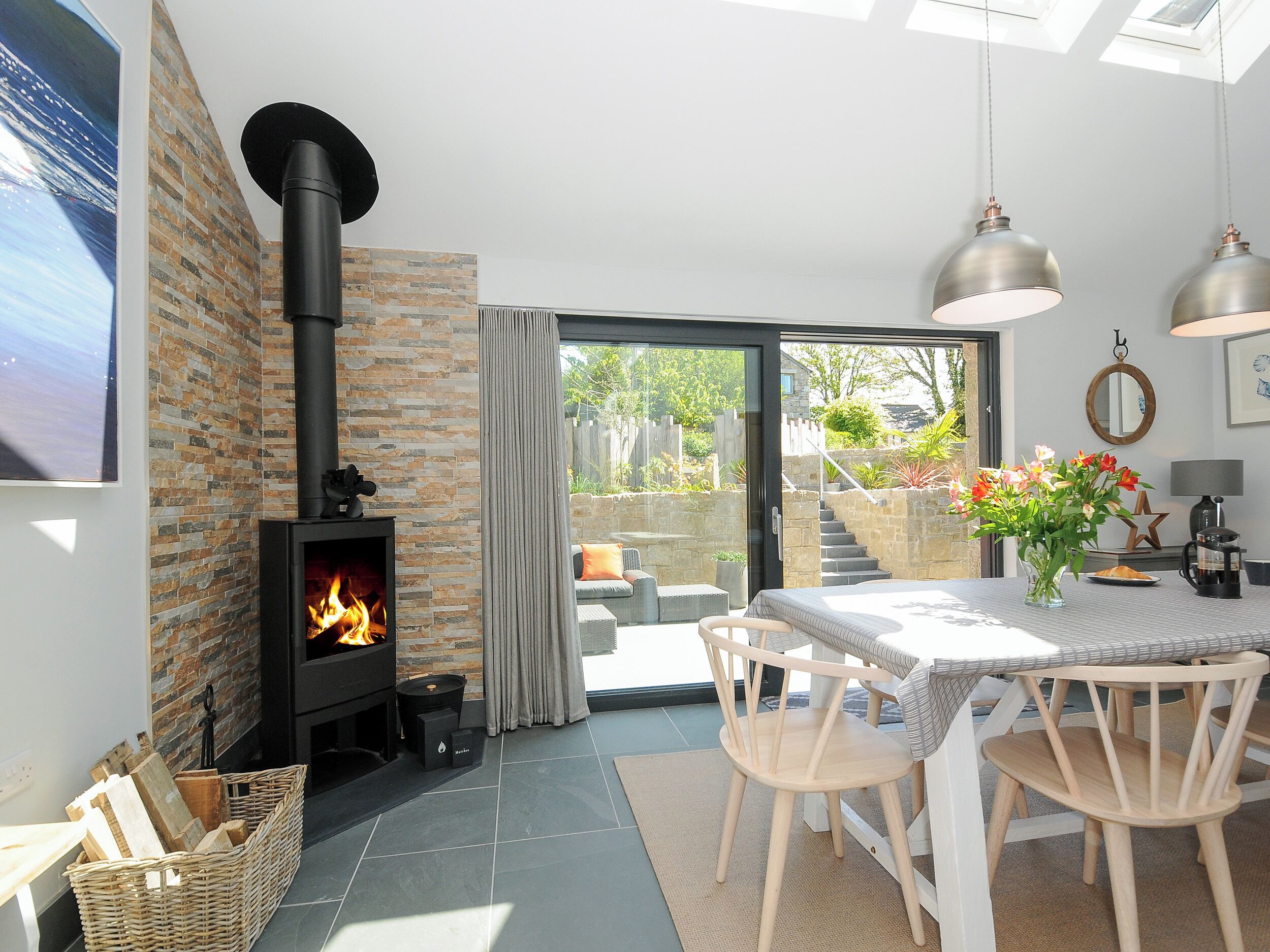 A cozy living room with a fireplace, a dining area with a table and chairs, and a view of the outdoors.