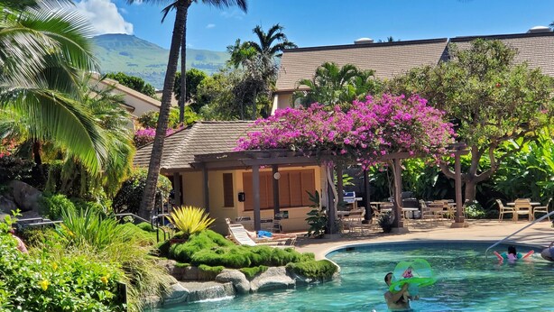 Ein Resort mit Pool, Palmen und einem Gebäude mit überdachter Terrasse.