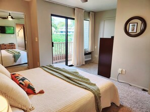 Habitació d'hotel amb un llit, una finestra gran, un ventilador de sostre, una televisió i un quadre penjat a la paret.