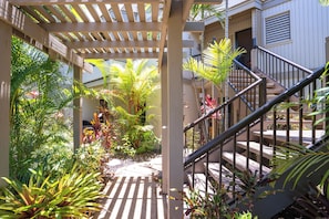 A covered outdoor area with a wooden pergola, a staircase, and various tropical plants. - Wailea Ekolu #306 Panoramic Ocean Views on Wailea Golf Course, Wifi, A/C (Wailea)