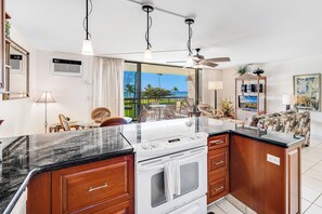 Una cocina moderna con una isla grande, horno empotrado y vista al océano.