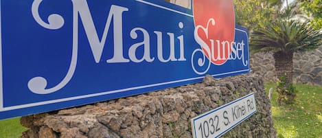 Un panneau bleu indiquant « Maui Sunset » et « 1032 S. Kihei Rd. ».