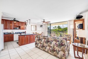 A spacious kitchen with wooden cabinets, a central island, and a dining area with a sofa and chairs.