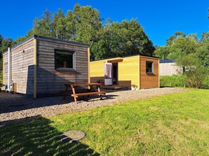 A wooden cabin with a picnic table and a small porch. - The Posh Bothy Spean Bridge (Roybridge)