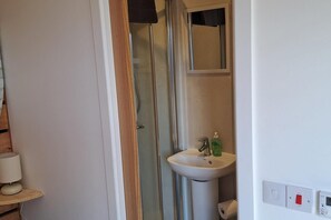 A bathroom with a glass shower enclosure, a white sink, and a mirror above it. - The Posh Bothy Spean Bridge (Roybridge)