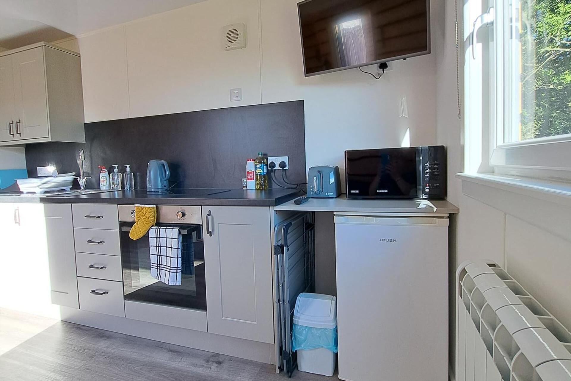 Una cocina compacta equipada con microondas, tostadora, hervidor y un refrigerador pequeño.