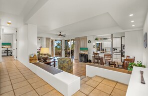 A spacious living area with a sofa, armchairs, and a dining table. A kitchen is visible in the background with modern appliances.
