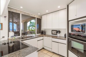 A modern kitchen with granite countertops, stainless steel appliances, and a view of the outdoors.