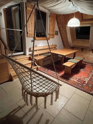 A cozy room with a hammock, wooden furniture, and a large window. - Welcome to Haus Tannenzäpfle (Waldachtal)