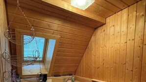 Pieni, käytännöllinen keittiö, jonka seinät ovat puuta, ja jossa on kattovalaisin, pesuallas ja astiateline.