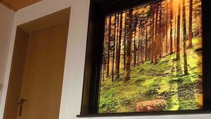 Portaat, joissa on puinen kaide, johtavat huoneeseen, jossa on suuri ikkuna, josta avautuu näkymä metsään.