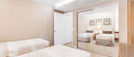 A hotel room with two beds, a large mirror, and a door leading to another room.