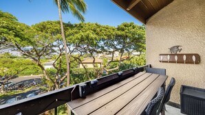 Eine Holzterrasse mit Tisch und Stühlen, mit Blick auf eine Wohngegend mit Bäumen und geparkten Autos.