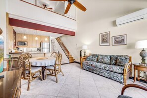 Un vaste espace de vie comprenant une table à manger, des chaises, un canapé et un escalier menant à l’étage supérieur.