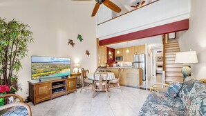 Ein geräumiges Wohnzimmer mit Fernseher, Essbereich und Küche.