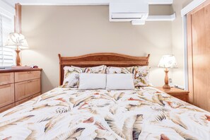 Une chambre à coucher comprenant un lit, une tête de lit en bois, deux lampes de chevet, une table de chevet et une armoire en bois.
