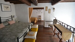 A bedroom with two beds, a desk, and a chair. There is a window with curtains, a wall with framed pictures, and a wooden ceiling. - Elegant Apartment for 3 in Firenze With Elevator (Florence)