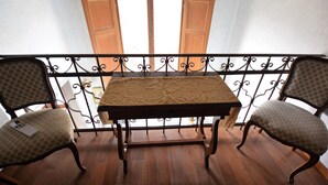 A balcony with a table and two chairs, wooden floor, and a view of a building through open doors. - Elegant Apartment for 3 in Firenze With Elevator (Florence)