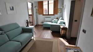 A living room with a sofa, a small table, and a window with wooden shutters. - Elegant Apartment for 3 in Firenze With Elevator (Florence)