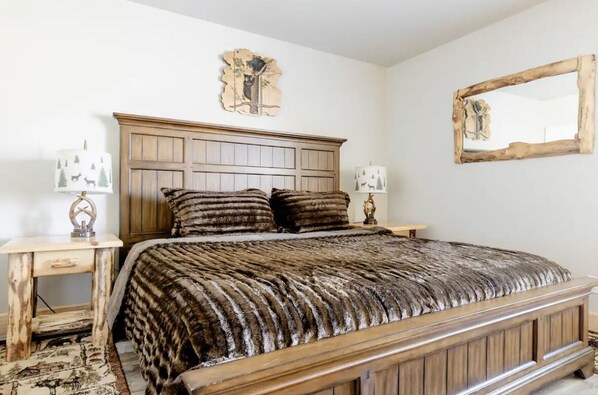 Un dormitorio con una cama de madera, dos mesitas de noche y un espejo grande en la pared.