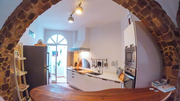 Une cuisine dotée d’une arche en pierre, de meubles blancs, d’un plan de travail en bois et d’un four encastré.