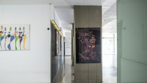 Un pasillo con instalaciones de arte moderno en las paredes y una puerta de cristal que da a otra zona.