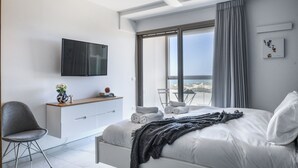 Un dormitorio moderno con una cama, televisión, escritorio y silla.