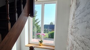 Eine Treppe mit Holzspindeln führt zu einer Zwischenebene mit einem Fenster mit Blick auf einen Garten.