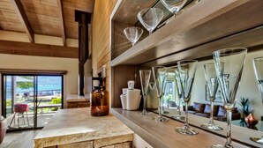 A kitchen counter with a stone backsplash, a bottle, and several wine glasses.