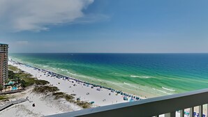 Ein Strand mit freiem Blick auf den Ozean, einem sandigen Ufer und einem Gebäude im Hintergrund.