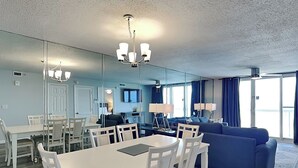 Ein modernes Wohnzimmer mit Essbereich, einem großen Spiegel und einem blauen Sofa.