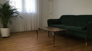 Ein Wohnzimmer mit einem grünen Sofa, einem Holztisch und einer Topfpflanze.