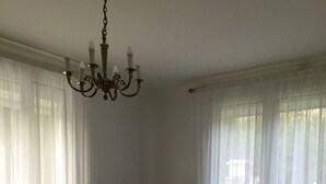 Ein Wohnzimmer mit Holzboden, einem grünen Sofa, einem Tisch mit Pflanze und einer Kristallleuchtre.