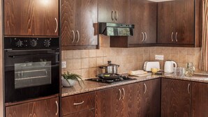 Una cocina con armarios de madera oscura, horno empotrado, microondas y estufa a gas.