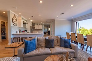Een moderne woonkamer met een bank, een salontafel, en een eethoek met stoelen.
