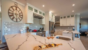 A modern kitchen with a marble island, stainless steel appliances, and a clock on the wall. - Designer Ranch w/Gourmet Kitchen and Downtown Views. (Paso Robles)