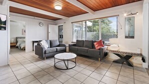 Ein modernes Wohnzimmer mit zwei grauen Sofas, einem runden Couchtisch und einer Holzbalkendecke.